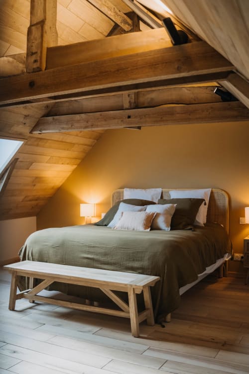 Cozy loft bedroom at Le Clos d'Omaha with exposed wooden beams, comfortable bed, and warm lighting
