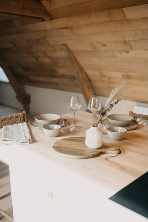 Elegantly set dining table at Le Clos d'Omaha with white bowls, wine glasses, and wooden accents under wooden beams