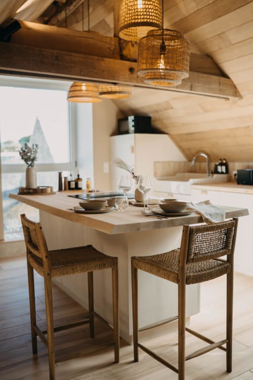Modern dining area in Suite Lushoto at Le Clos d'Omaha with wooden table, woven chairs, and pendant lights overlooking the