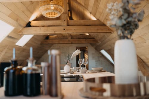 Rustic wooden A-frame suite at Le Clos d'Omaha with elegant dining area, pendant light, and garden views