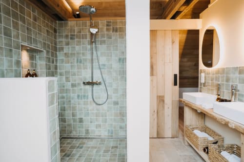 Modern bathroom in Suite Lushoto at Le Clos d'Omaha with green tile shower, wooden vanity, and heated mirror