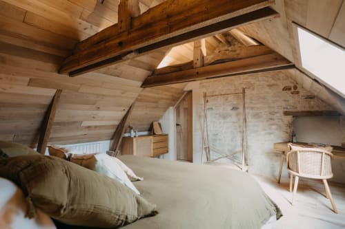 Rustic attic suite with exposed wooden beams, natural light, and minimal furnishings at Le Clos d'Omaha