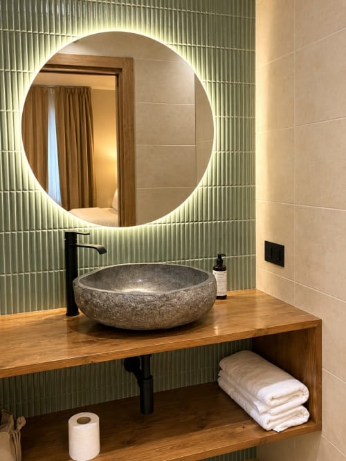 Baño moderno en suite del Hostel Tinto Dreams con lavamanos de piedra, espejo circular iluminado y tocador de madera