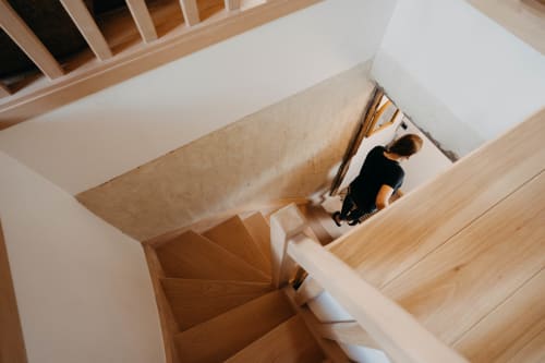 Overhead view of wooden staircase at Le Clos d'Omaha hotel, Englesqueville, with guest descending to second floor