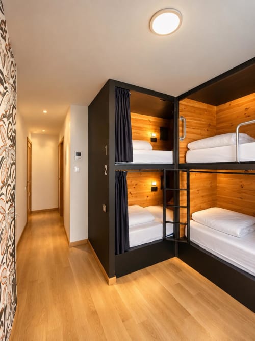 Habitación cuádruple moderna con literas privadas, paredes de madera y escalera metálica en Tinto Dreams Hostel de Haro