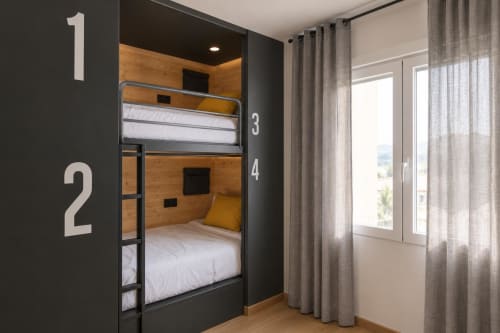 Habitación con literas en Tinto Dreams Hostel en Haro: estructura metálica, interior de madera, ropa de cama blanca y gran ventana con cortinas