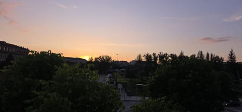Vista del atardecer sobre Monforte de Lemos desde el apartamento Bikarte Alojamientos con árboles y arquitectura recortados en dorado