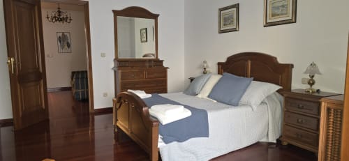 Elegante dormitorio en apartamento Casa Amma de Bikarte Alojamientos, Monforte de Lemos, con muebles de madera y vistas emblemáticas