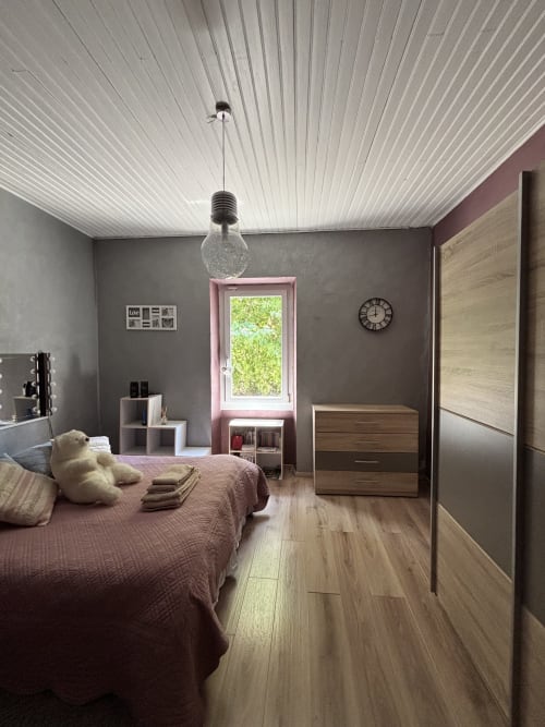Chambre cosy au Mas Provençal à Bollène avec fenêtre rose, mobilier bois et plafond ondulé