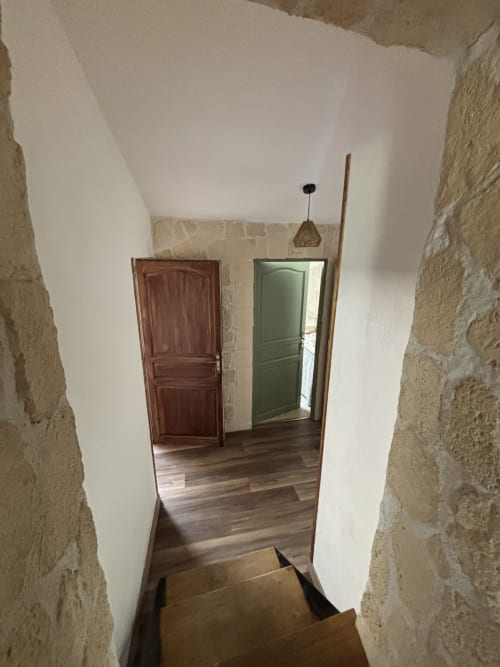 Couloir aux murs de pierre, portes en bois et luminaire suspendu au Mas Provençal, Bollène