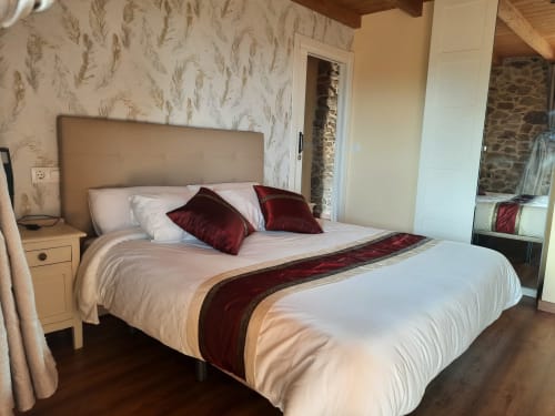 Elegante dormitorio en Bikarte Alojamientos con cama queen, acentos burdeos, cabecero beige y papel tapiz decorativo en Ribeira