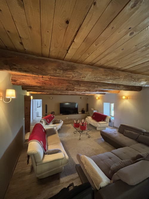 Spacieux séjour du Mas Provençal avec poutres en bois, sièges confortables, télévision et accents rouges à Bollène
