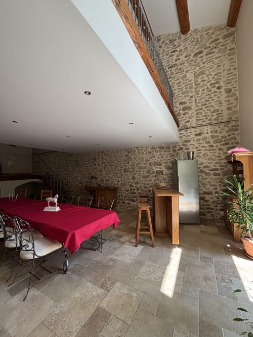 Stone dining room at Mas Provençal in Bollene, France with red tablecloth and wooden beams
