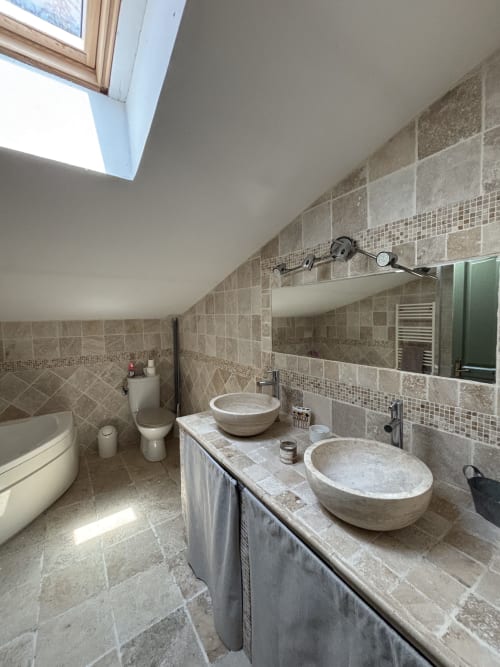 Salle de bain luxueuse au Mas Provençal avec vasques en pierre, carrelage mural, puits de lumière et équipements modernes à Bollène
