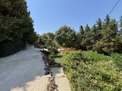 Allée de gravier traversant les jardins luxuriants du Mas Provençal à Flanc De Colline, chambres d'hôtes en Provence à Bollène, France,