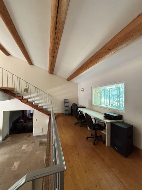 Espace de travail en loft à Mas Provençal, Bollène : poutres apparentes, parquet, bureau avec chaises, grande fenêtre