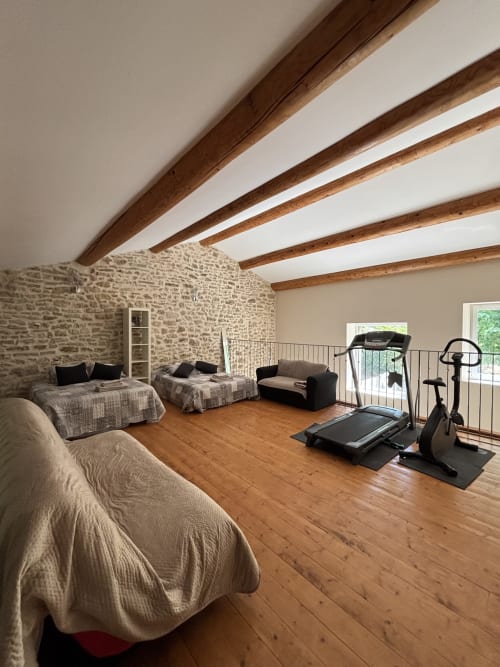 Spacieuse chambre loft au Mas Provençal avec poutres en bois apparent, murs en pierre, lits et équipements de fitness, Bollène