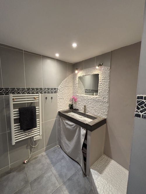 Salle de bains moderne à la Mas Provençal B&B à Bollène avec carrelage blanc texturé, vanité foncée, sèche-serviettes chauffant et éclairage encastré