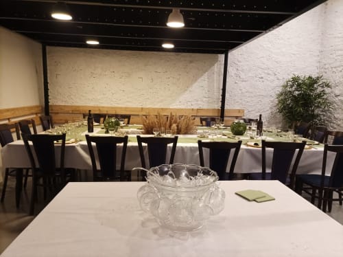 Elegant dining room at Domaine Le Piboul with white tablecloths, black chairs, and white stone walls.