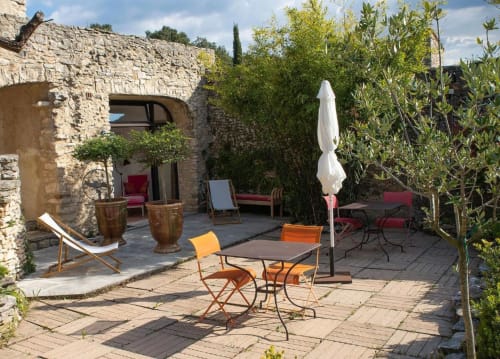 Cour pavée rustique du gîte Le Clos des Amandiers à Simiane-la-Rotonde avec salon extérieur et parasols
