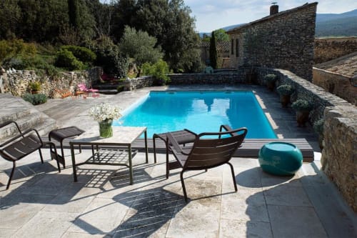 Piscine turquoise au Clos des Amandiers, terrasse en pierre avec transats à Simiane-la-Rotonde