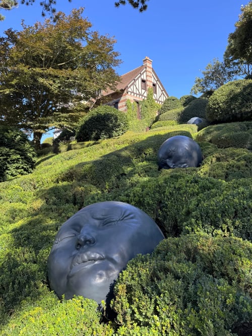 Têtes sculpturales noires nichées dans les haies taillées de l'hôtel New Windsor à Étretat, France