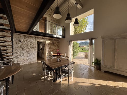 Salle à manger lumineuse à La Petite Plaine, Clansayes : table en bois, murs en pierre et vue champêtre