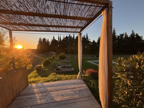 Pergola en bois avec voilages donnant sur le jardin au coucher du soleil, La Petite Plaine B&B à Clansayes
