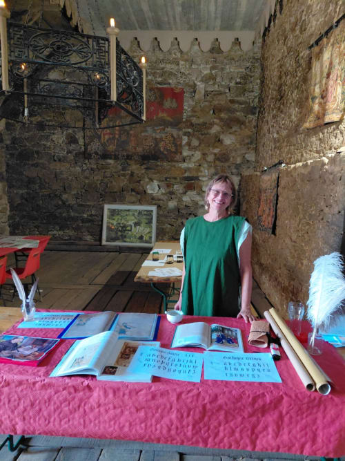 Femme à l'accueil avec des livres dans une salle en pierre historique au Domaine de Châlus-Chabrol, Châlus