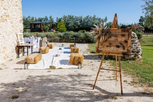 Cérémonie rustique en plein air à La Petite Plaine B&B à Clansayes avec bottes de foin, signalétique en bois et bâtiments en pierre