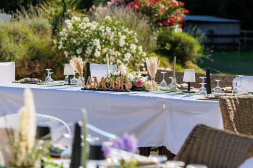 Élégant espace de dîner en plein air à La Petite Plaine à Clansayes avec table blanche, compositions florales et jardin pittoresque