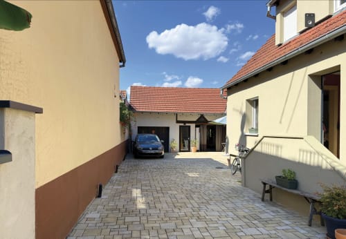 Cour pavée du gîte l'Atelier des Dépendances à Lipsheim avec toits en terre cuite et voiture garée