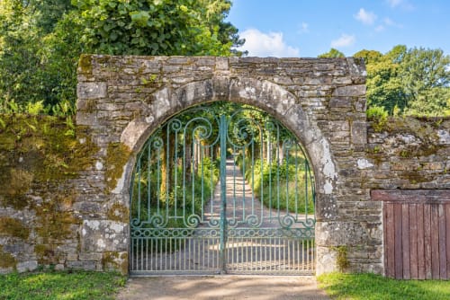 Portail en fer forgé et arche en pierre à l'entrée du site abbatial de Saint-Maurice, à Clohars-Carnoët, dans le Finistère Sud.