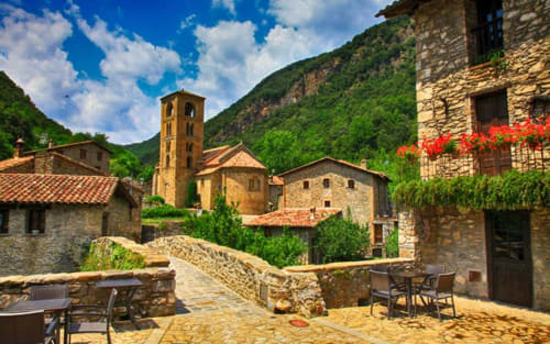 Place médiévale en pierre à l'hôtel Casa Etxalde à Gérone, Espagne, avec clocher et montagnes verdoyantes