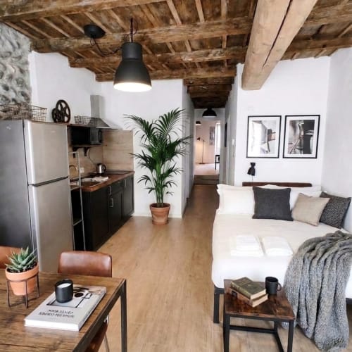 Moderno monolocale a Bergamo con travi in legno a vista, angolo cottura, letto e zona living