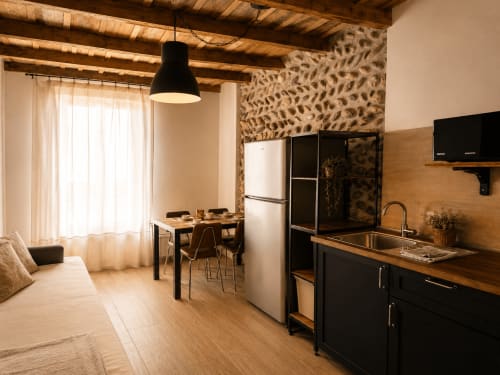 Monolocale moderno a Bergamo con cucina a vista, zona pranzo e soggiorno con travi in legno e accenti in pietra