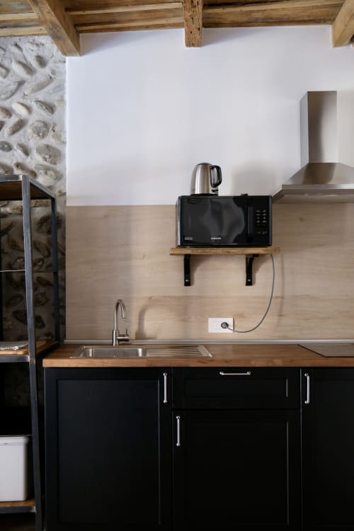 Piccolo angolo cottura moderno a Bergamo con mobili neri, piano di lavoro in legno, microonde, lavello acciaio e