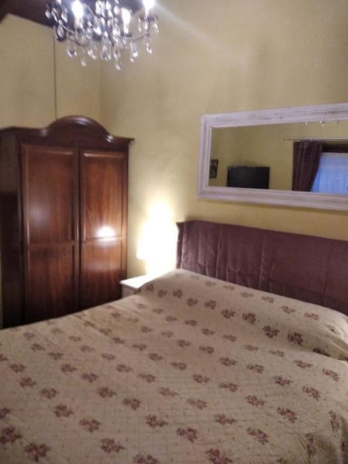 Camera economia dell'Antico Belvedere con guardaroba in legno, letto, specchio e lampadario a Pieve Fosciana