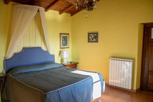 Camera luminosa giallo acceso con letto a baldacchino blu presso Antico Belvedere B&B a Pieve Fosciana, Italia