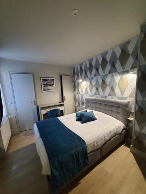 Chambre double moderne à l'hôtel New Windsor ETRETAT avec accents bleus, tête de lit géométrique et mobilier contemporain