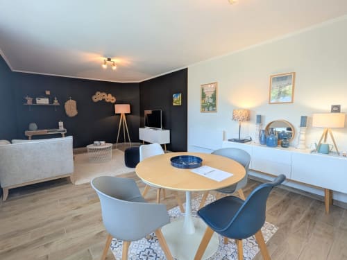 Spacieux séjour ouvert du gîte Le Clos d'Émilie à Saint-Marcel avec table ronde, mur d'accent sombre et jardin