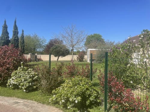 Le jardin du Clos d'Émilie à Saint-Marcel avec arbustes fleuris, cyprès et clôture verte