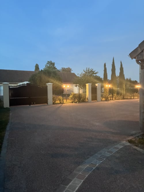 Entrée du gîte Le Clos d'Émilie au crépuscule avec portail illuminé et cyprès, Saint-Marcel