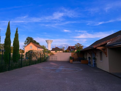 Cour du gîte Le Clos d'Émilie au crépuscule à Saint-Marcel avec jardins entretenus et château d'eau