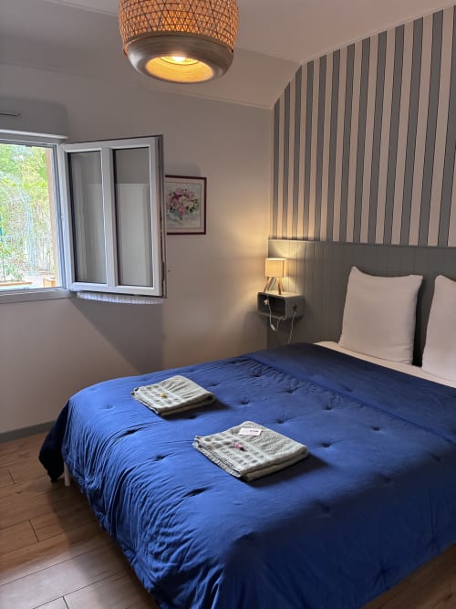 Chambre moderne du gîte Le Clos d'Émilie à Saint-Marcel avec literie bleue, lambris rayés et éclairage chaleureux