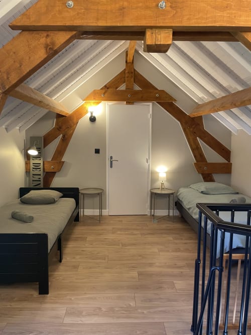 Chambre spacieuse du gîte Le Clos d'Émilie, Saint-Marcel, avec poutres apparentes, deux lits et plafond cathédrale