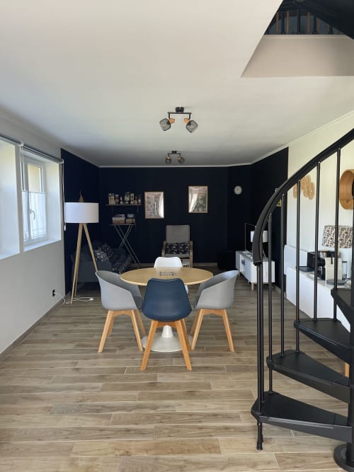 Salle à manger moderne au Clos d'Émilie avec table ronde, escalier hélicoïdal et mur d'accent foncé