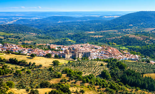 Vista aérea de Guadalupe, Cáceres con castillo histórico, edificios blancos y colinas boscosas en España