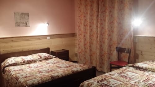 Chambre double à l'Hôtel Les Fleurs à Morzine avec lits jumeaux, boiseries et rideaux à fleurs