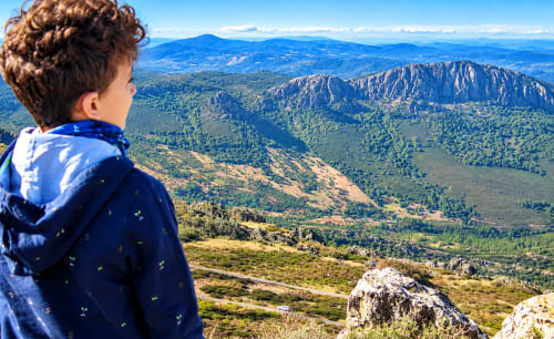 Niño contemplando el paisaje montañoso desde El descanso del peregrino en Guadalupe, Cáceres, España